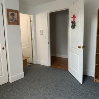 An empty room with a carpeted floor, open doors, and wall decorations.