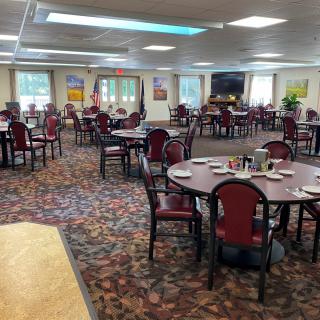 A spacious dining area with neatly arranged tables and chairs on a carpeted floor.