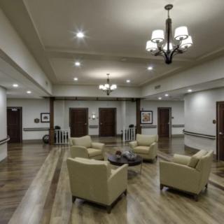 A spacious lobby with comfortable seating, elegant chandeliers, and wood flooring.