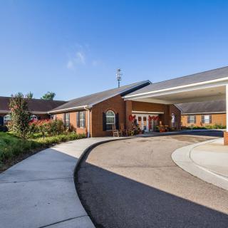 A building with a driveway and landscaped entrance under a clear blue sky.