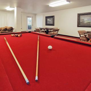 A cozy game room featuring a red-felt pool table and comfortable seating.