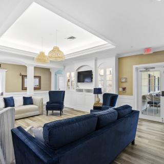 A modern living room with blue sofas and chairs, featuring elegant lighting and wooden flooring.