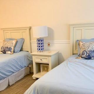 A cozy bedroom with two twin beds, featuring blue bedding and a decorative lamp on a nightstand.