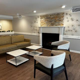 A modern and cozy living room setup with stylish furniture and a decorative fireplace.