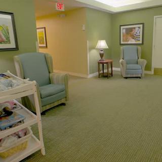 A cozy waiting room with green walls, comfortable chairs, and a magazine rack.