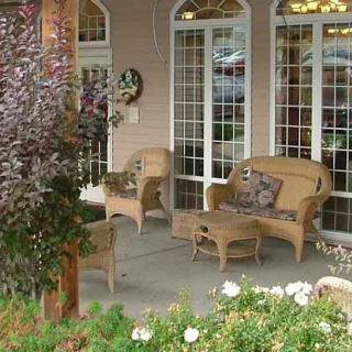 A cozy porch with wicker furniture and lush greenery.