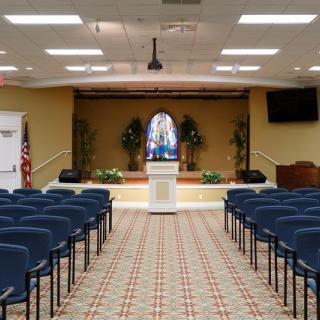 Interior view of a church with rows of pews and a podium on stage.