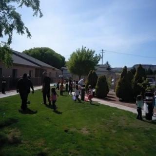 A sunny day in the park with children and adults gathering.