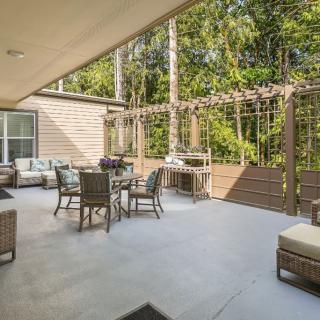 A spacious outdoor patio with comfortable seating and a pergola, surrounded by lush greenery.