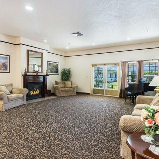 A spacious living room with comfortable seating, a fireplace, and a grand piano.