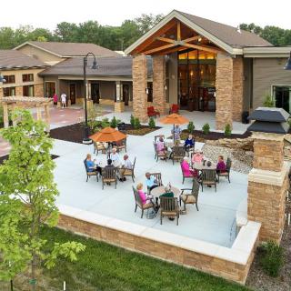 A modern building with an outdoor patio area featuring tables and chairs occupied by people enjoying the space.