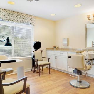 A cozy and well-lit hair salon interior with styling chairs, a mirror, and a window providing natural light.