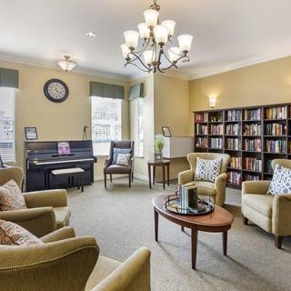 A cozy living room with a piano, bookshelves, and comfortable seating.