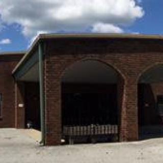 A brick building with a covered entrance under a partly cloudy sky.
