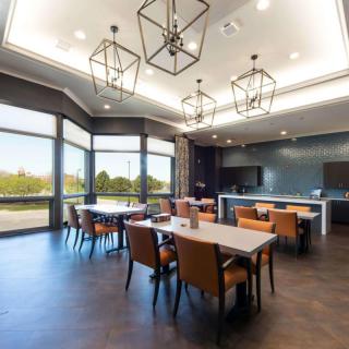 A modern dining area with stylish lighting and ample natural light streaming through large windows.