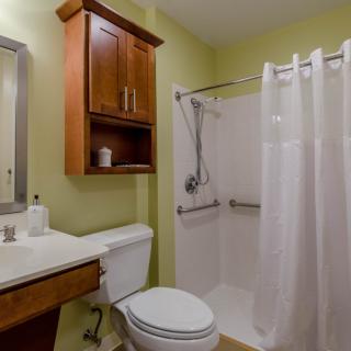 A small bathroom with a toilet, sink, and shower area featuring a white curtain.