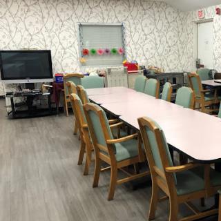 A spacious meeting room equipped with a long table and comfortable chairs, featuring a television and decorative wallpaper.