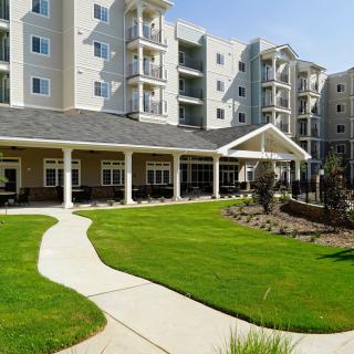 A modern residential apartment building with well-maintained landscaping and a neatly manicured lawn.