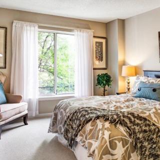 A cozy and well-decorated bedroom with natural lighting from a large window.