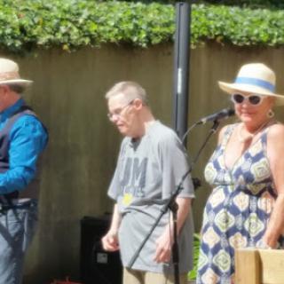A lively outdoor music performance featuring a group of musicians enjoying the sunny day.
