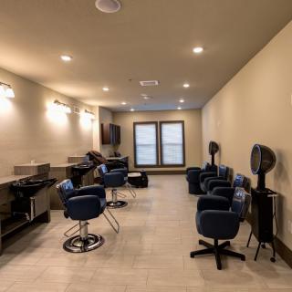A modern hair salon interior with stylish chairs and well-lit mirrors.