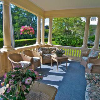 A cozy porch with wicker furniture and lush greenery, perfect for relaxing outdoors.