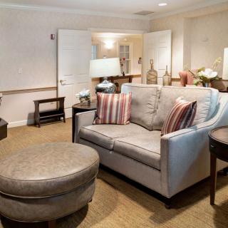 A cozy living room with a comfortable sofa and ottoman, decorated with striped pillows and soft lighting.