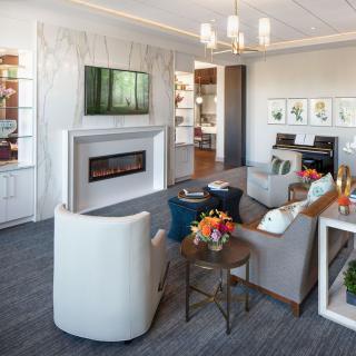 A modern living room with stylish decor, featuring a fireplace, chandelier, and comfortable seating area.