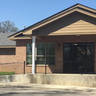 A modern single-story brick building with large windows, featuring a welcoming entrance.