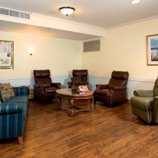 A cozy living room with armchairs and a sofa surrounding a central table on a wooden floor.