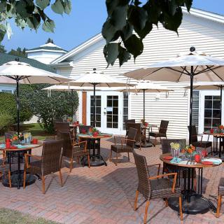 A charming outdoor restaurant patio with umbrellas and neatly arranged tables and chairs under a sunny sky.