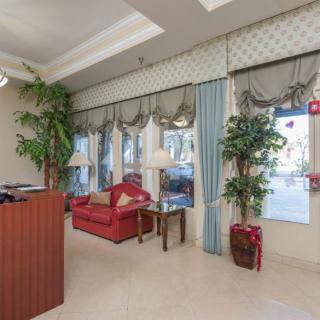 A cozy lobby with a red sofa, wooden reception desk, and large windows adorned with drapes.