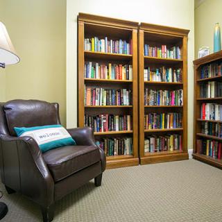 A cozy reading room with bookshelves filled with books and a comfortable leather chair.
