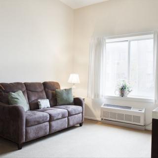 A cozy living room with a sofa, lamp, and large window.
