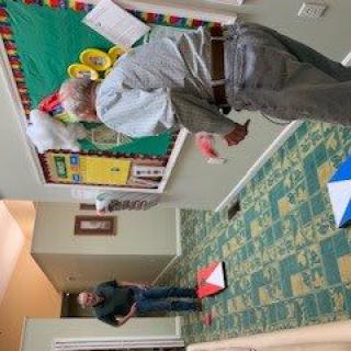 Two people interacting in a hallway near a bulletin board.