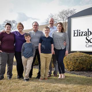 A cheerful family poses together outside the Elizabeth School, showcasing a sense of community and togetherness.