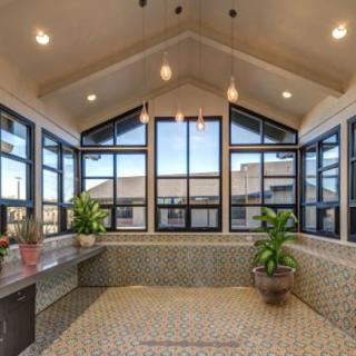 A spacious sunroom with large windows and potted plants, featuring a tiled floor and ample natural light.