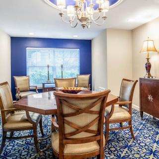 A well-decorated dining room featuring a wooden table and chairs, a chandelier, and elegant carpeting.