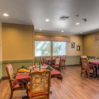 A cozy dining room with neatly arranged tables and chairs, well-lit by natural and artificial light.