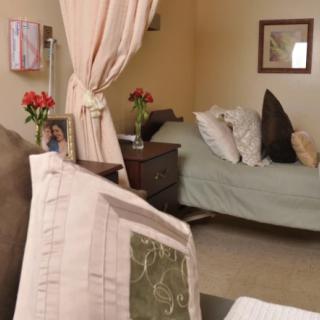 A cozy hospital room with a bed, pillows, and floral decor.