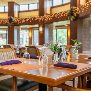 A beautifully arranged dining area with wooden tables, purple napkins, and decorative flowers.