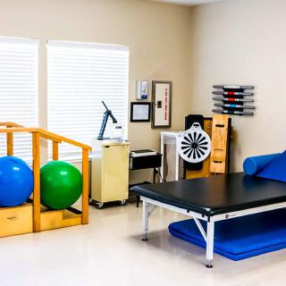 A well-equipped physical therapy room with exercise balls and a treatment table.