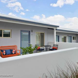 A modern outdoor patio featuring seating and a small table alongside a building with a minimalist design.