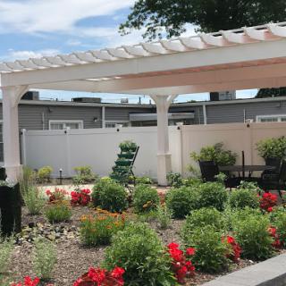 A beautifully landscaped garden featuring vibrant flowers and a white pergola, perfect for relaxation.