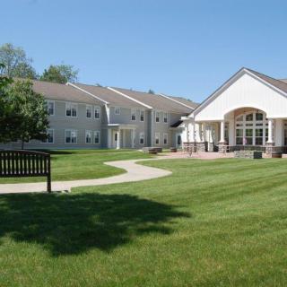 A scenic view of a campus with green lawns, pathways, and buildings under a clear blue sky.