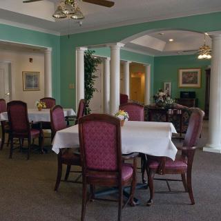 A cozy dining room with elegantly set tables and chairs, featuring soft lighting and tasteful decor.