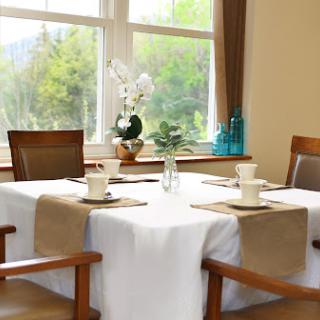 A beautifully set dining table with natural light streaming in through the window.
