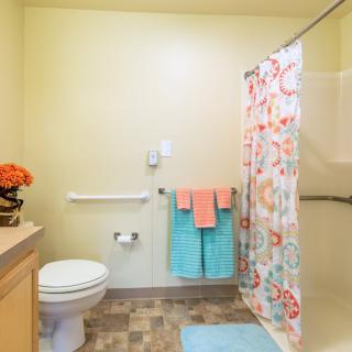 A clean and brightly decorated bathroom with a floral shower curtain and colorful towels.