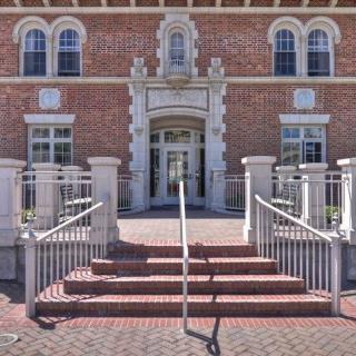A historic brick building with an elegant entrance and stairs.