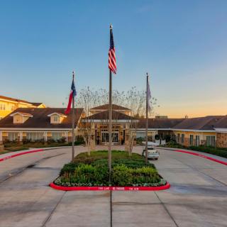 A building entrance with flags and a landscaped driveway at sunset.